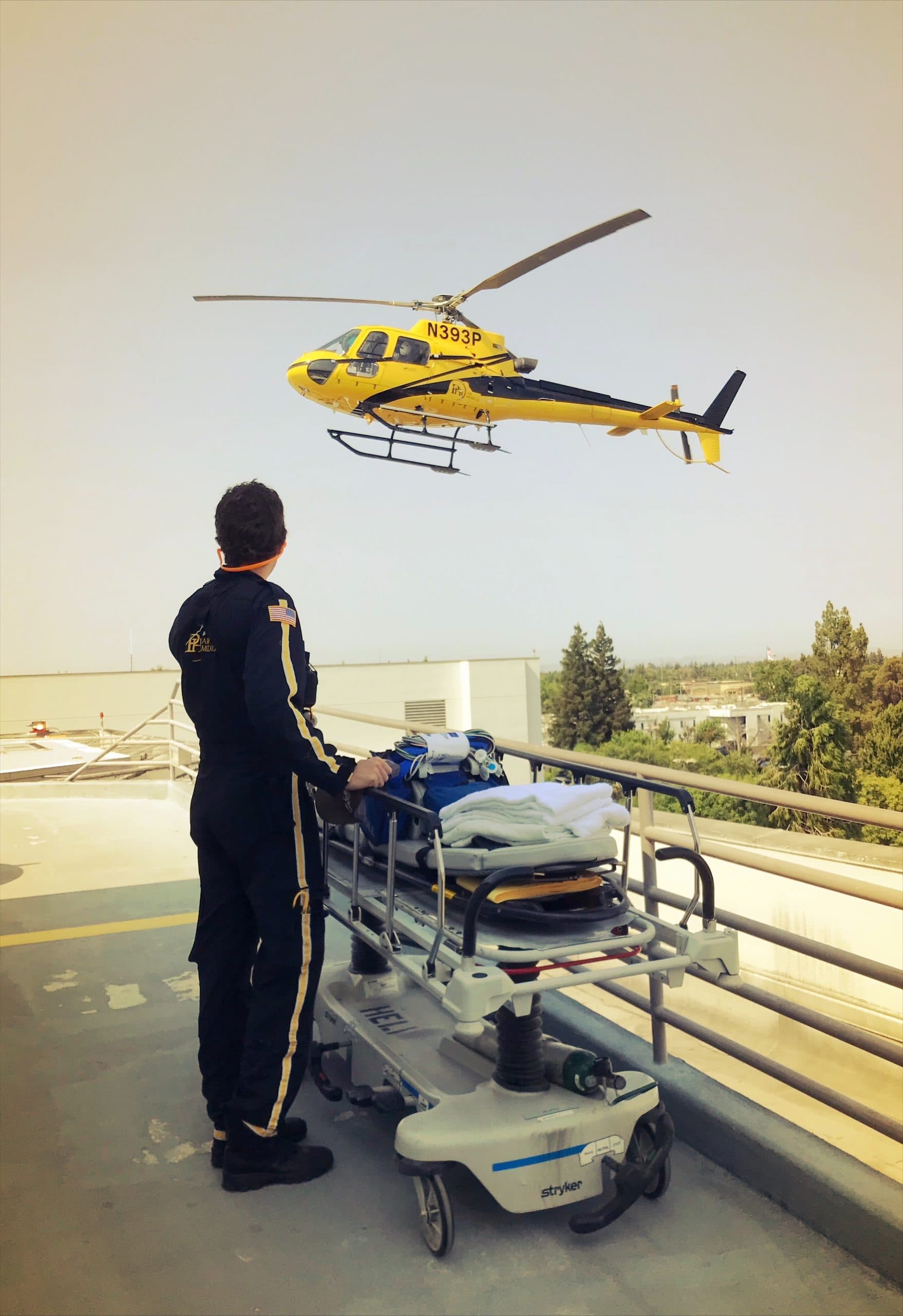 Emergency medical technician preparing to assist with helicopter rescue using the Searle Starter helicopter, showcasing advanced rescue equipment on a rooftop helipad.