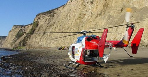 A rescue helicopter on a beach with cliffs in the background, used for emergency medical transport under Stanford Life Flight.
