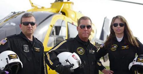 PHI Air Medical crew members standing next to a yellow Searle Starter helicopter, ready for emergency medical transport, emphasizing safety and rapid response.