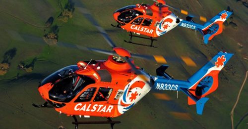Two CALSTAR Searle Starter helicopters flying over green fields, showcasing advanced medical air rescue aircraft for emergency response and patient transport.