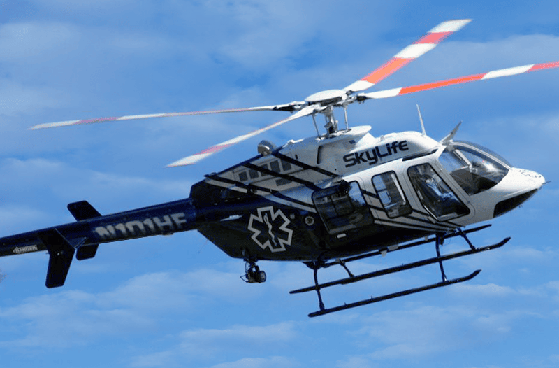 A SkyLife air ambulance helicopter flying in clear blue skies, providing emergency medical transport services for critical patients.