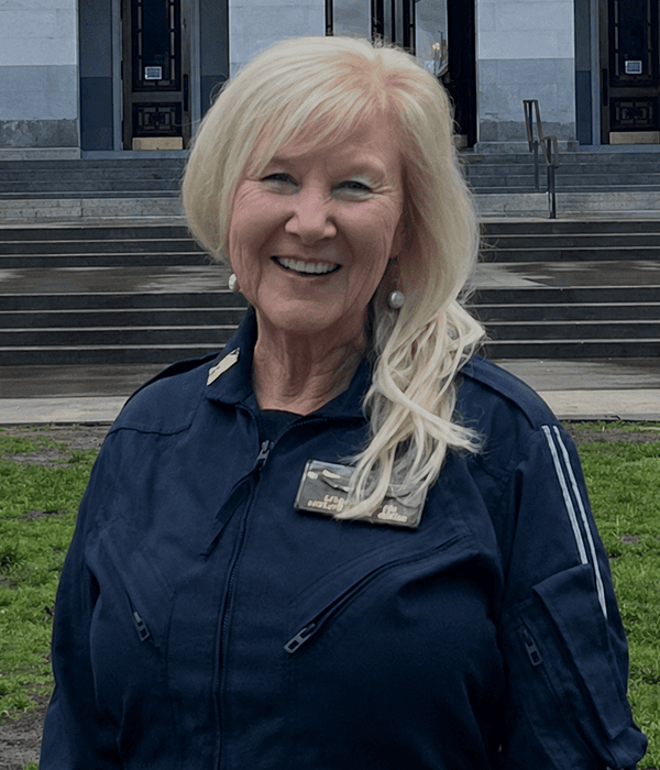 Searle Starter, a woman with blonde hair in a navy jacket, standing outside a government building, representing leadership and community engagement.